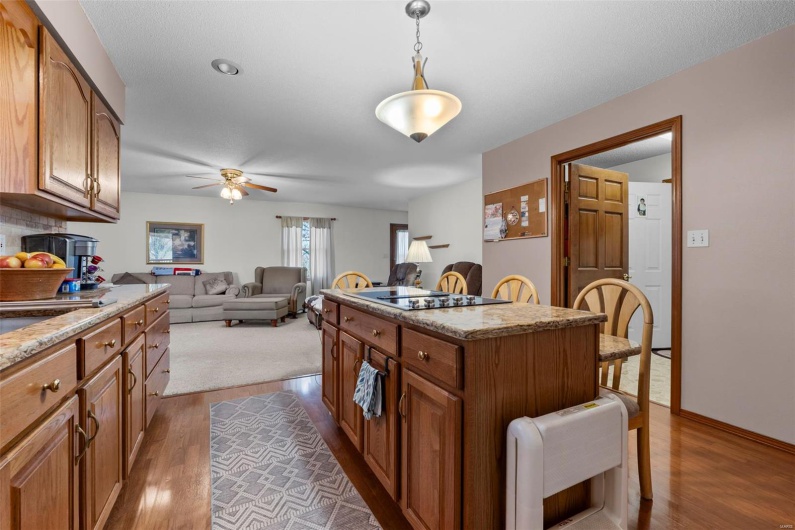 Kitchen featuring a center island, black electric cooktop, a kitchen breakfast bar, dark wood finished floors, and brown cabinets
