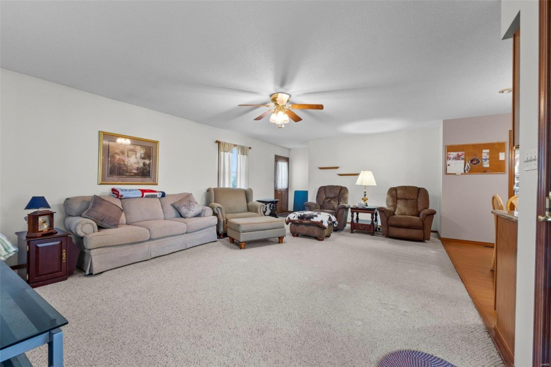 Carpeted living area featuring ceiling fan
