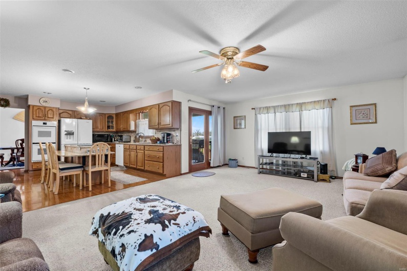 Living room with a textured ceiling, baseboards, and a ceiling fan