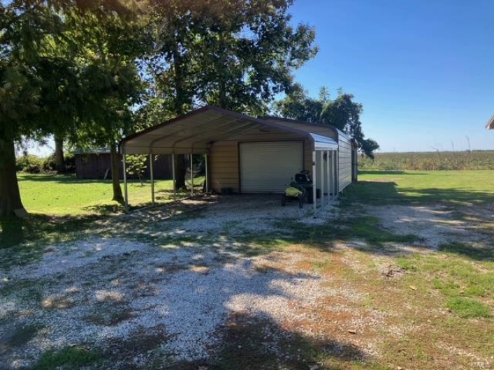 Garage featuring a lawn and a carport