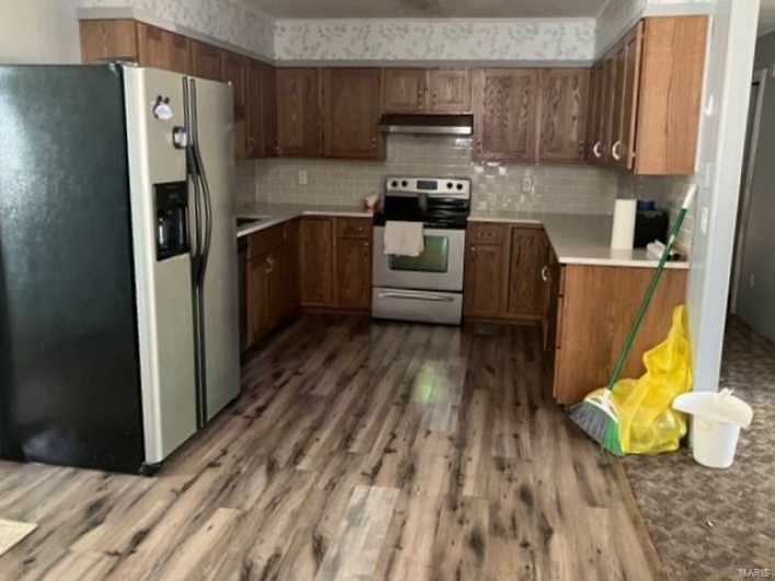 Kitchen featuring appliances with stainless steel finishes, decorative backsplash, and hardwood / wood-style floors