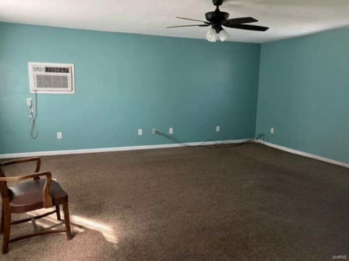 Carpeted spare room featuring ceiling fan and a wall unit AC