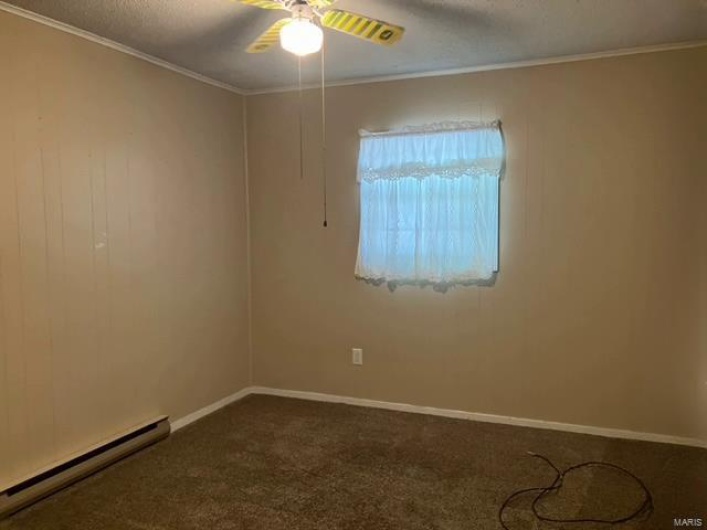 Carpeted spare room with a textured ceiling, ceiling fan, baseboard heating, and crown molding