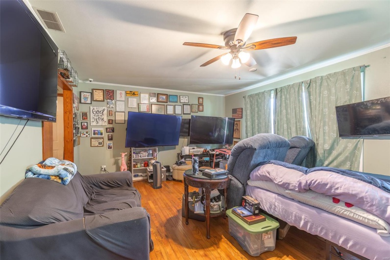Living room featuring ornamental molding, visible vents, ceiling fan, and wood finished floors