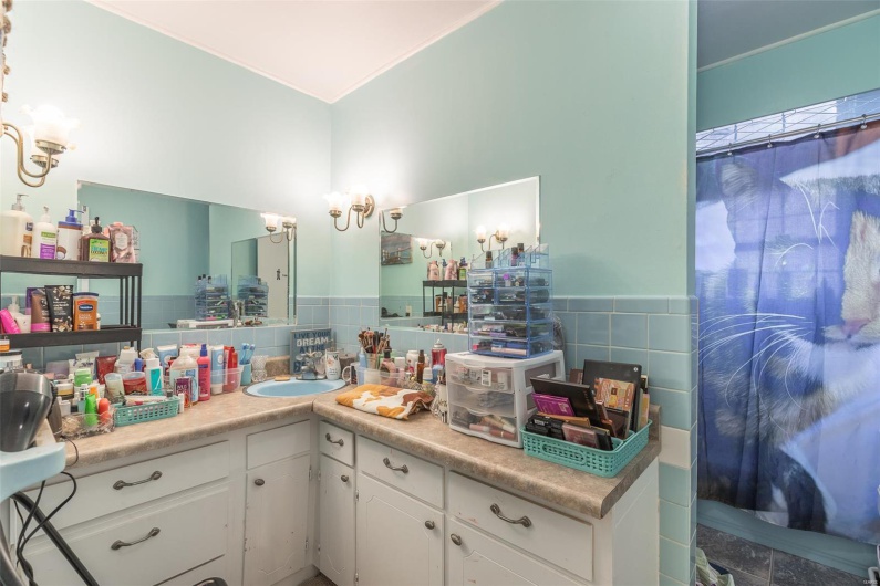 Bathroom with vanity, a notable chandelier, a wainscoted wall, and tile walls