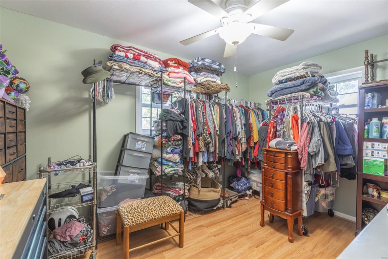 Walk in closet with wood finished floors and a ceiling fan