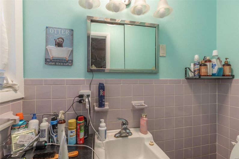 Half bath featuring tile walls, a sink, and a wainscoted wall