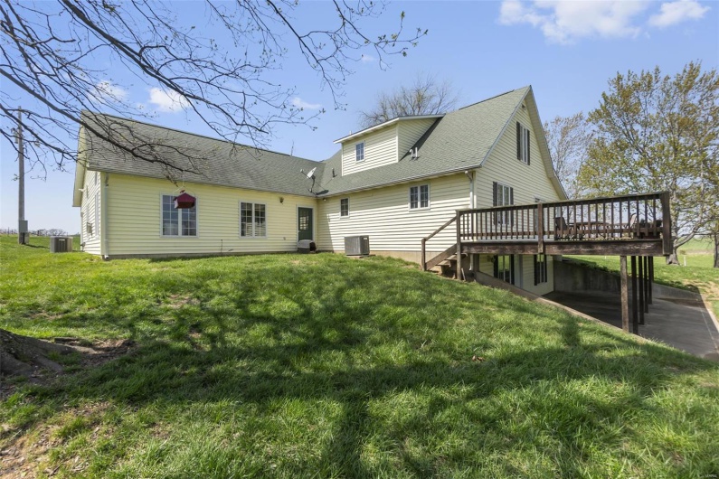 Rear view of house with a wooden deck, a yard, and central AC