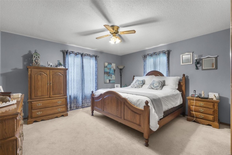 Bedroom featuring light carpet, a textured ceiling, and ceiling fan