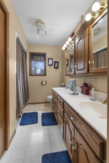 Bathroom featuring tile patterned floors, double vanity, visible vents, toilet, and a sink