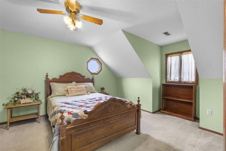 Carpeted bedroom featuring lofted ceiling, a ceiling fan, visible vents, and multiple windows