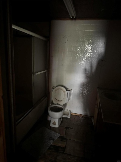 Bathroom featuring tile patterned floors, toilet, and tile walls