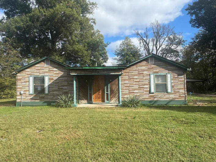 Rear view of property featuring a yard and a carport