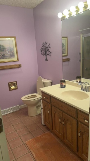 Bathroom with visible vents, toilet, vanity, a shower stall, and tile patterned floors