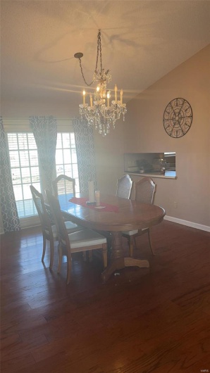 Dining space featuring a notable chandelier, a textured ceiling, baseboards, and wood finished floors