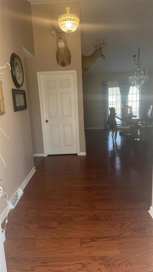 Corridor with wood finished floors, visible vents, and an inviting chandelier
