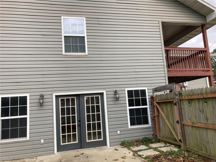 Side of house with french doors, fence, a patio, and a gate
