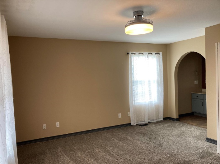 Carpeted spare room featuring arched walkways and baseboards