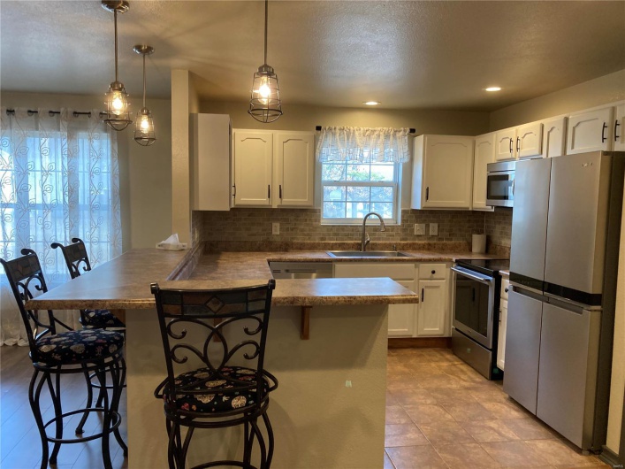 Kitchen with appliances with stainless steel finishes, a breakfast bar area, a peninsula, and a sink