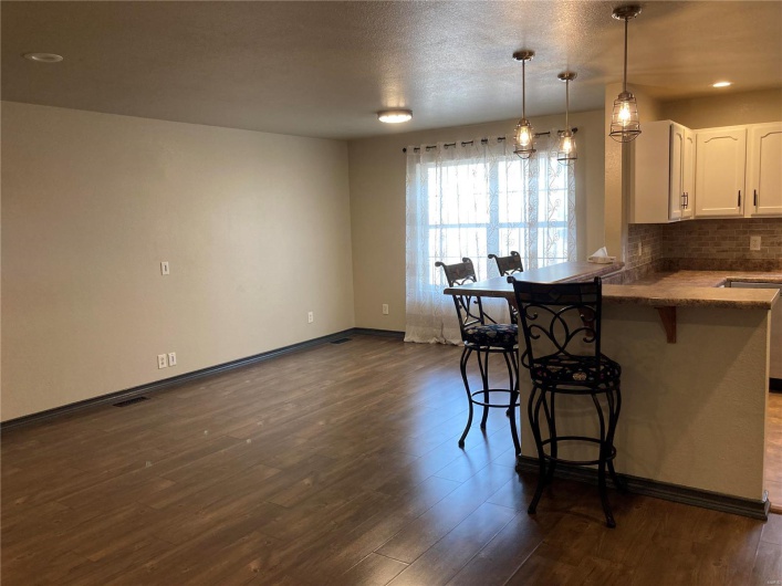 Kitchen with backsplash, dark wood-type flooring, a breakfast bar area, and white cabinetry