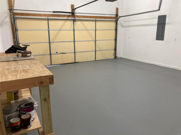 Garage featuring electric panel, a garage door opener, and baseboards