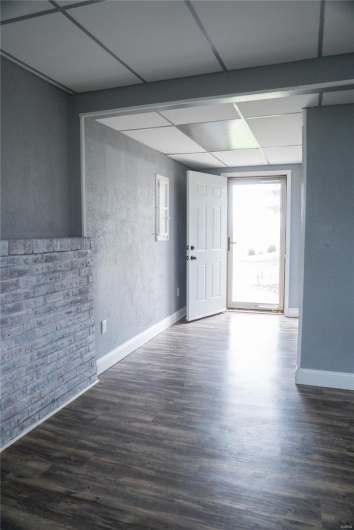 Unfurnished room featuring baseboards, a drop ceiling, and wood finished floors