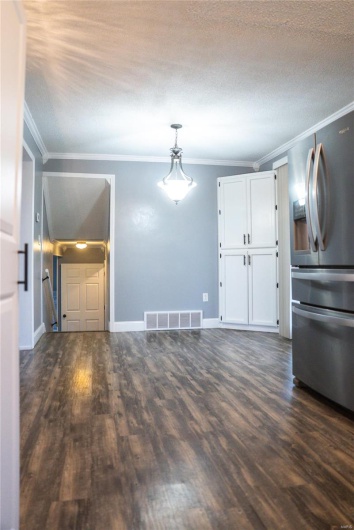 Unfurnished living room featuring ornamental molding, dark wood-style floors, and visible vents