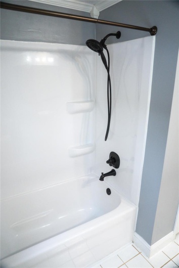 Bathroom featuring ornamental molding, baseboards, tile patterned flooring, and shower / washtub combination