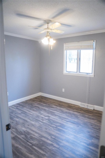 Unfurnished room featuring dark wood finished floors, ornamental molding, and ceiling fan
