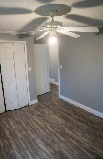 Unfurnished bedroom featuring a closet, baseboards, a ceiling fan, a textured ceiling, and dark wood-type flooring