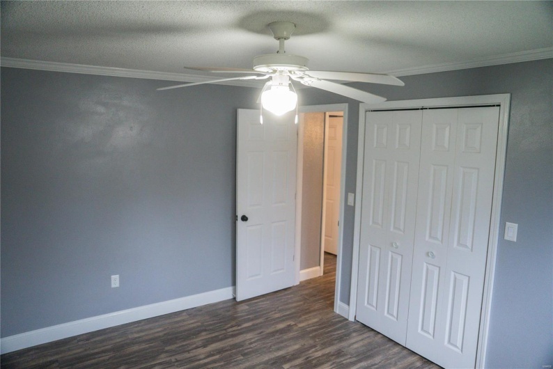 Unfurnished bedroom featuring a closet, baseboards, a textured ceiling, crown molding, and dark wood finished floors