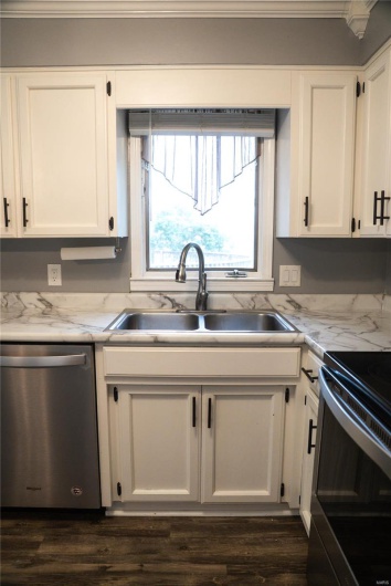 Kitchen featuring a sink, stainless steel dishwasher, and white cabinets