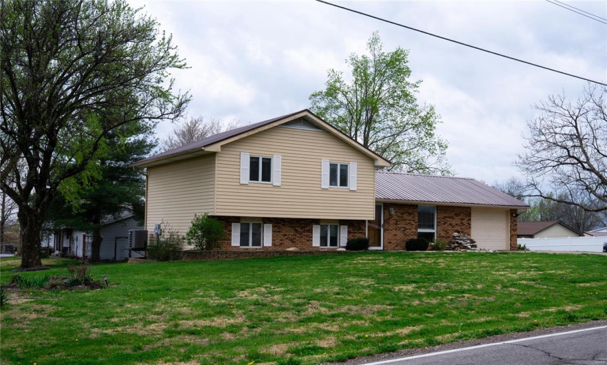 Tri-level home featuring brick siding, a front lawn, and an attached garage