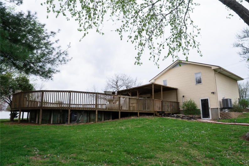 Rear view of property with central AC, a wooden deck, and a lawn