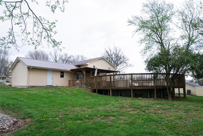Rear view of house with metal roof, a deck, and a lawn