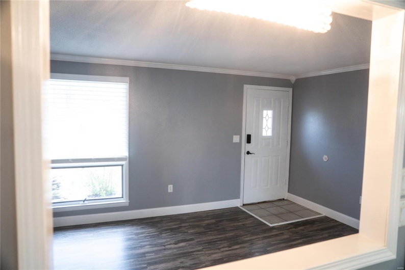 Entrance foyer with crown molding, wood finished floors, and baseboards
