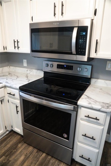 Kitchen featuring stainless steel appliances, dark wood-type flooring, and white cabinetry