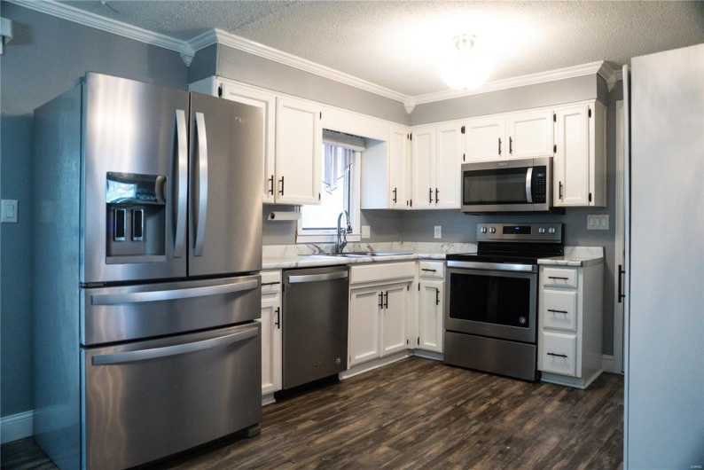 Kitchen featuring light countertops, a sink, white cabinetry, and stainless steel appliances