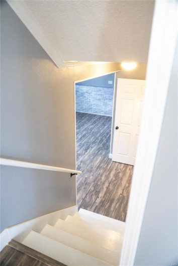 Stairs featuring a textured ceiling, crown molding, and wood finished floors