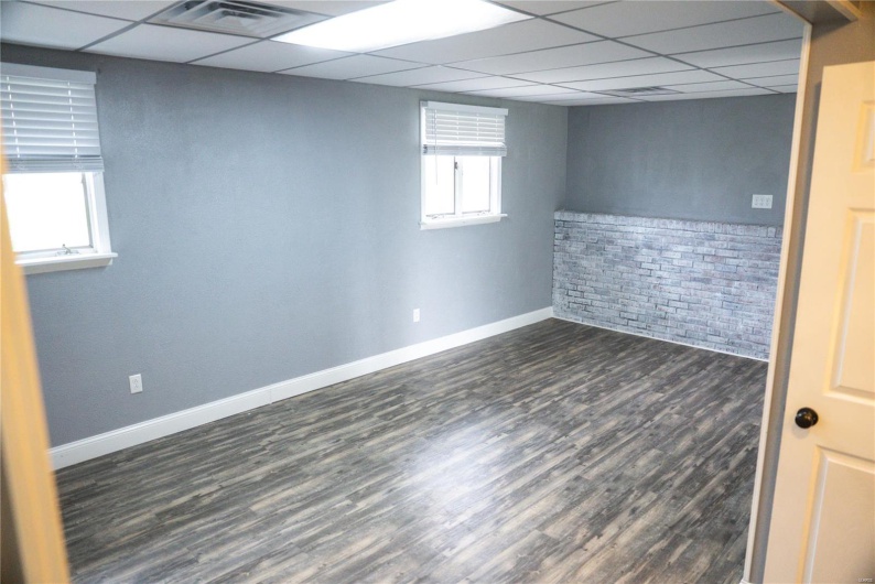 Basement featuring baseboards, dark wood-style flooring, a drop ceiling, and visible vents