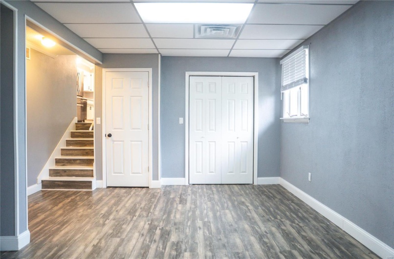 Below grade area featuring a paneled ceiling, wood finished floors, baseboards, and visible vents