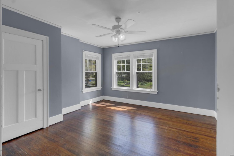 Unfurnished room featuring crown molding, ceiling fan, baseboards, and hardwood / wood-style flooring