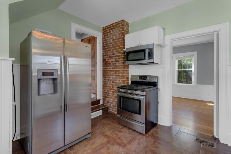 Kitchen with dark wood-type flooring, white cabinetry, visible vents, and stainless steel appliances