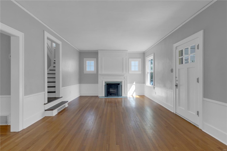 Unfurnished living room with a fireplace, wood-type flooring, visible vents, and crown molding
