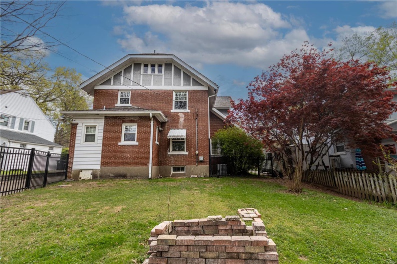 Rear view of property featuring brick siding, a fenced backyard, and a yard