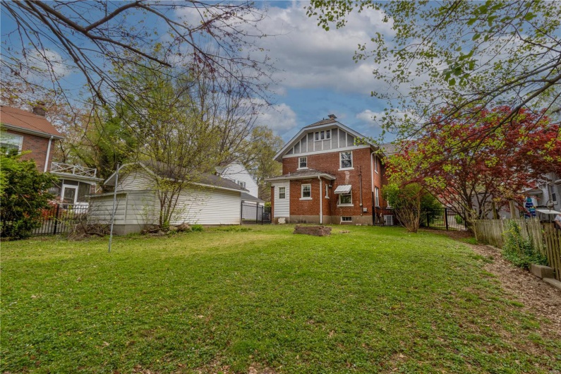 Back of house with a yard, brick siding, and a fenced backyard