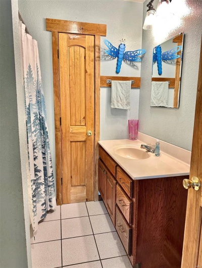 Full bathroom with tile patterned floors, vanity, and a textured wall