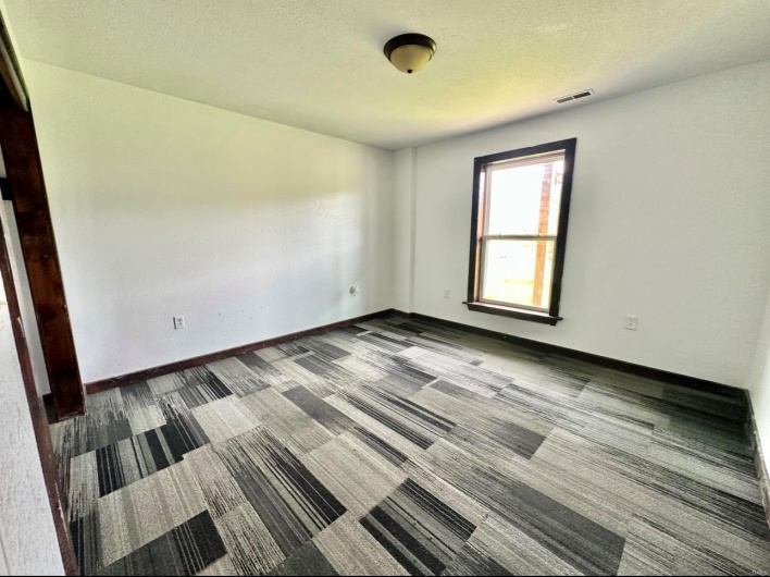 Carpeted spare room with visible vents, baseboards, and a textured ceiling