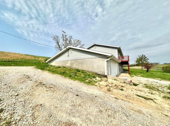 View of side of home featuring dirt driveway and a garage