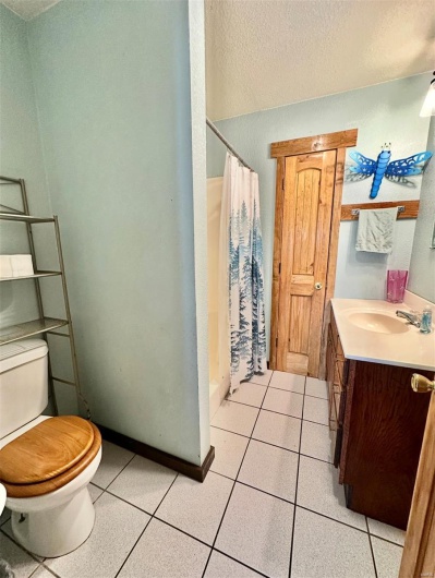 Full bath with a textured ceiling, a shower with curtain, vanity, tile patterned flooring, and toilet
